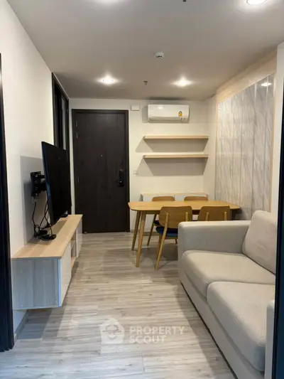 Modern living room with cozy sofa, wall-mounted TV, and dining area in stylish apartment.