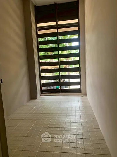 Spacious tiled balcony with wooden slatted windows offering a serene garden view.