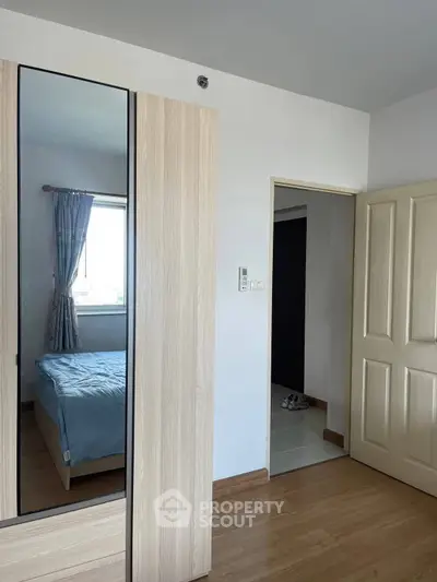Modern bedroom with wooden flooring and mirrored wardrobe