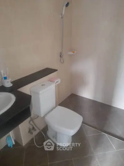 Modern bathroom with sleek fixtures and tiled flooring, featuring a shower and toilet.