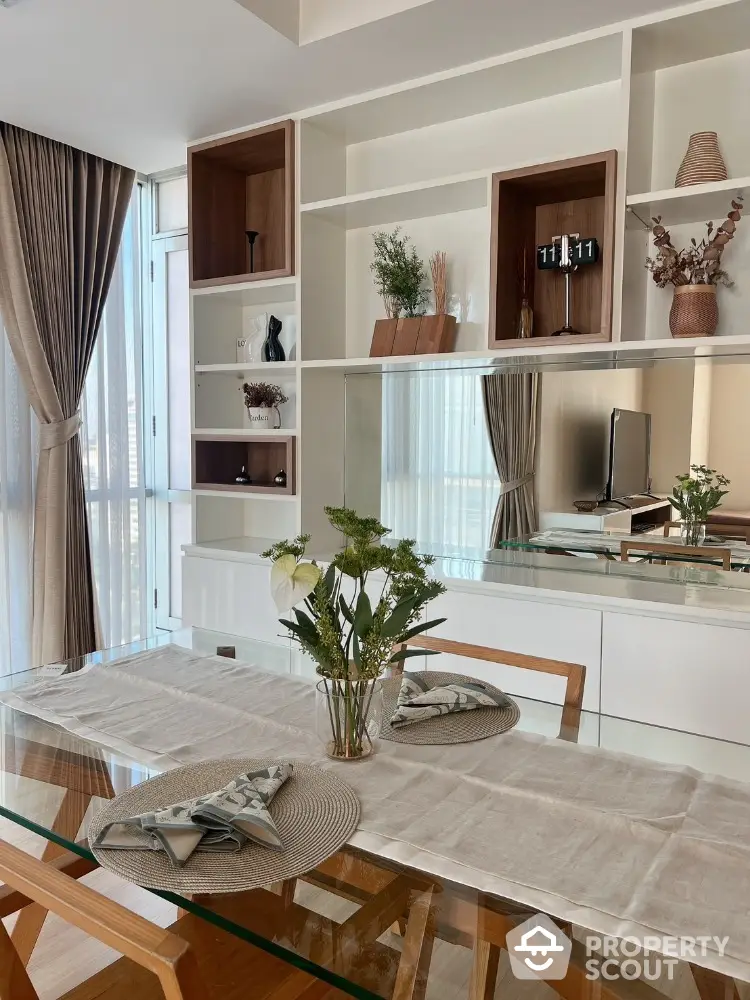 Elegant dining area with glass table and stylish shelving in modern apartment