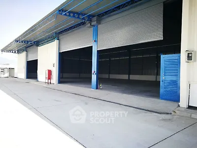 Spacious industrial warehouse with open roller doors and ample loading space.