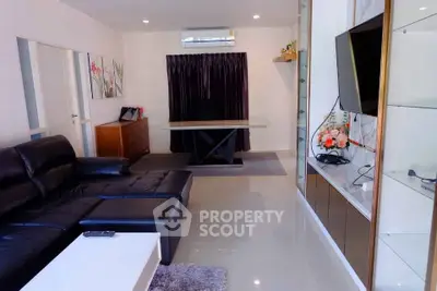 Modern living room with sleek black leather sofa and wall-mounted TV