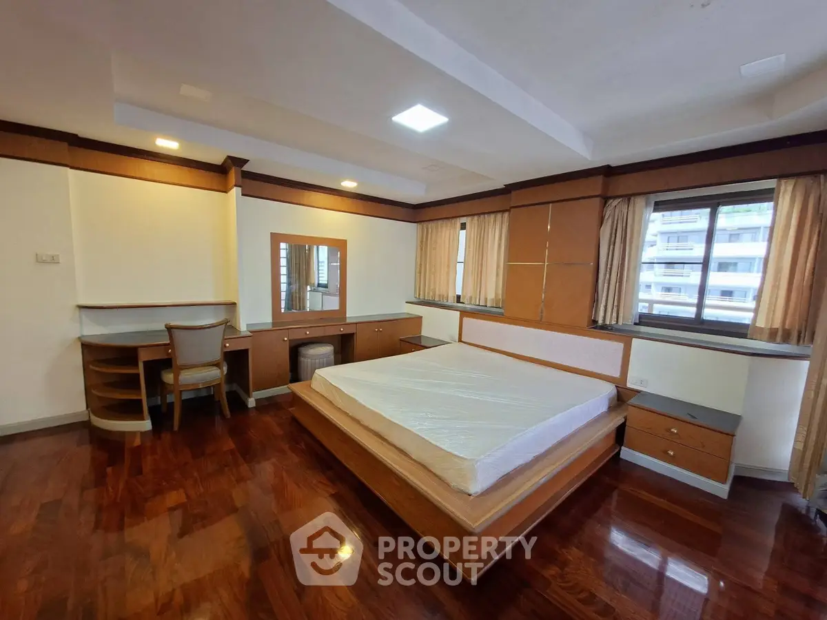 Spacious bedroom with elegant wooden flooring and built-in furniture in a modern apartment.