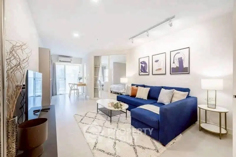 Modern living room with blue sofa and stylish decor in open-plan apartment.