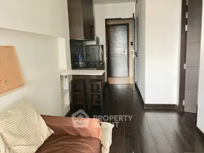 Cozy apartment interior with dark wood flooring and compact kitchen layout.