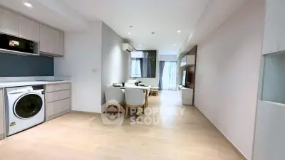 Modern open-plan living room with dining area and kitchen featuring sleek appliances and wooden flooring.