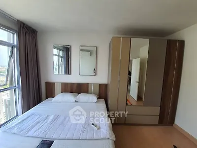 Spacious bedroom with modern wardrobe and large windows offering city views.