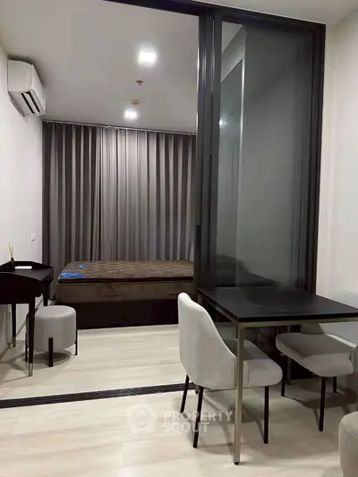 Modern studio apartment with sleek design and cozy furnishings, featuring a comfortable bed and dining area.