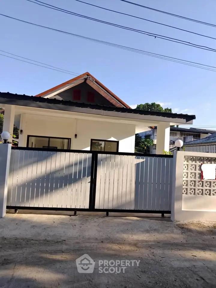 Charming single-story house with modern gate and sloped roof in a serene neighborhood.