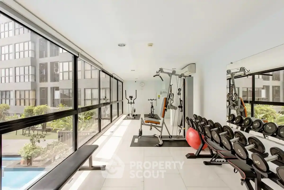 Modern gym with large windows and pool view in luxury apartment building.