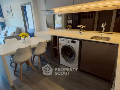 Modern open-layout kitchen with integrated washing machine and stylish dining area.