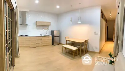 Modern open-plan kitchen and dining area with wooden flooring and stylish lighting.