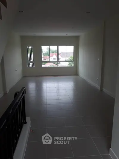 Spacious living room with large window offering natural light and neighborhood view.