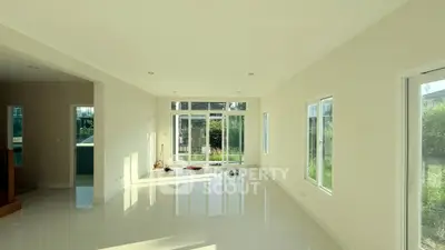 Spacious sunlit living room with large windows and garden view