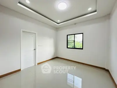 Spacious empty room with modern ceiling lights and large window view.