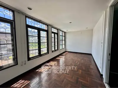 Spacious sunlit room with elegant parquet flooring and large windows