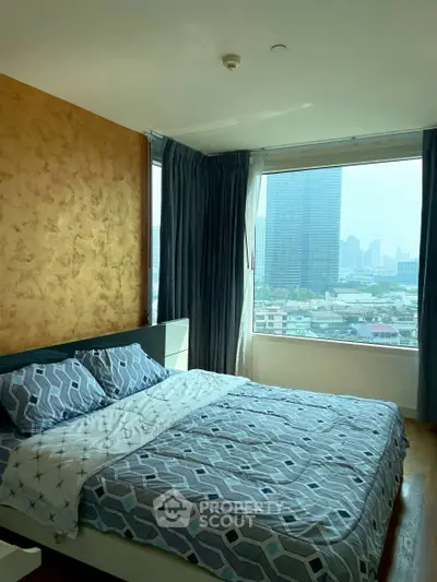 Spacious bedroom with large window offering stunning city views, featuring modern decor and cozy bedding.