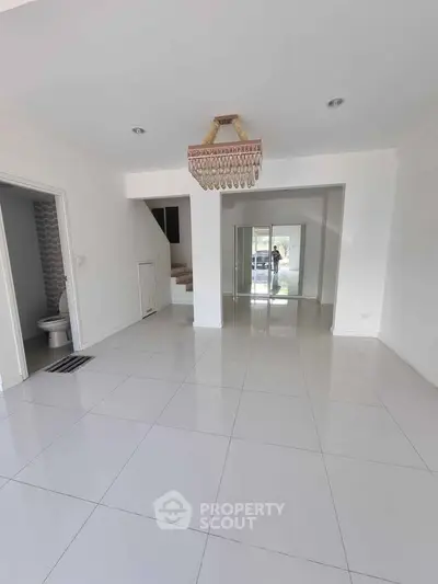 Spacious open-plan living area with elegant chandelier and modern tile flooring