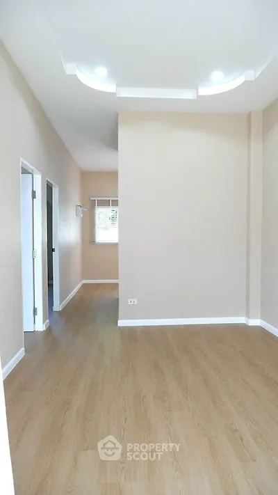 Spacious empty room with wooden flooring and modern ceiling lights