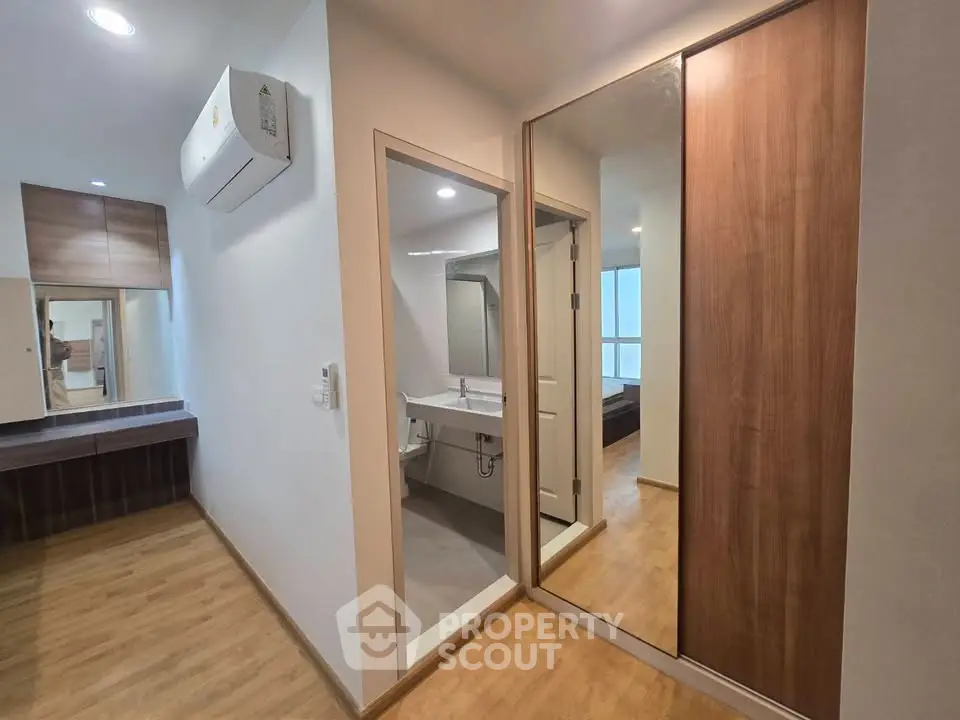 Modern apartment interior with wooden flooring, mirrored closet, and air conditioning unit.