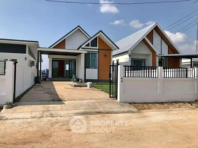 Charming modern house with spacious driveway and fenced yard under clear blue sky.