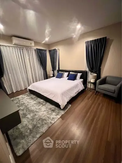 Elegant bedroom with cozy lighting, plush rug, and stylish curtains for a serene retreat.