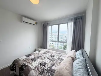 Bright and cozy bedroom with large window offering city views, perfect for relaxation and comfort.