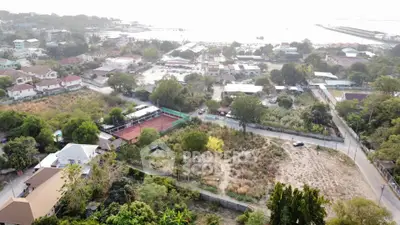 Aerial view of residential area with lush greenery and tennis court, showcasing serene suburban living.