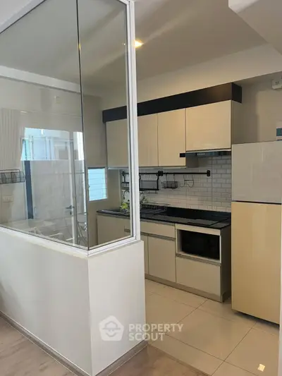 Modern kitchen with sleek cabinetry and glass partition in contemporary apartment.
