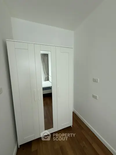 Modern white wardrobe in a minimalist bedroom with wooden flooring and neutral tones.