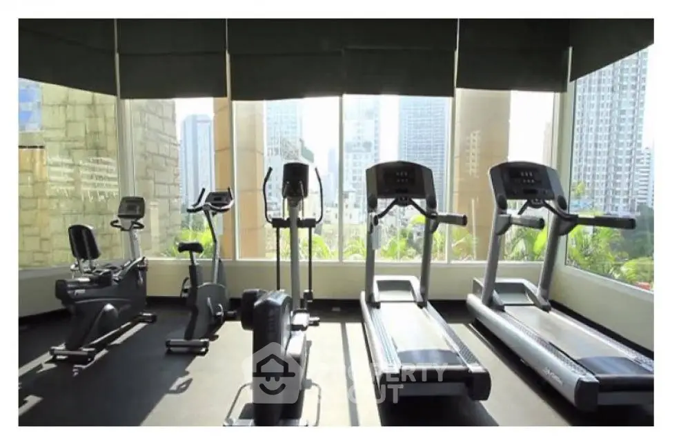 Modern gym with city view featuring treadmills and exercise bikes.