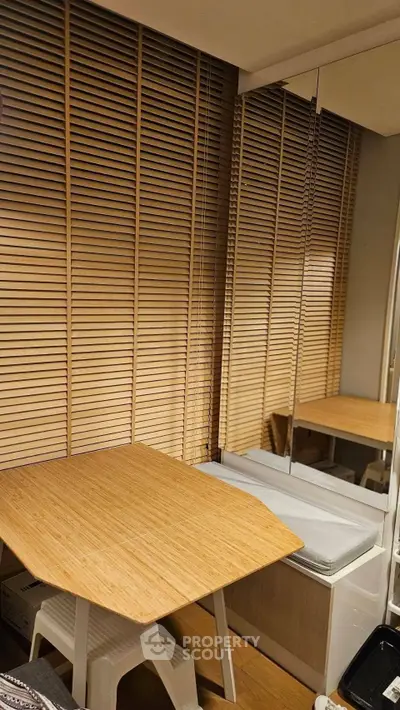 Cozy study nook with wooden table and blinds, perfect for productivity.