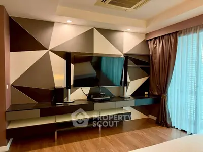 Modern living room with geometric wall design and large TV, featuring elegant curtains and wooden flooring.