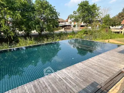 Luxurious outdoor pool with wooden deck and lush greenery, perfect for relaxation and leisure.