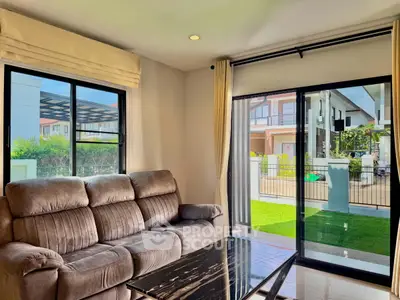 Spacious living room with plush sofa and large windows overlooking a modern garden view.