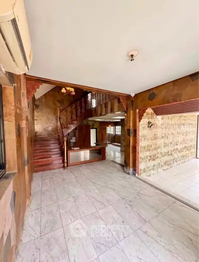 Spacious open-plan living area with elegant staircase and marble flooring