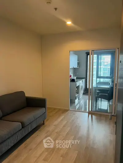 Modern apartment with cozy living room and sleek kitchen featuring washing machine and dining area.