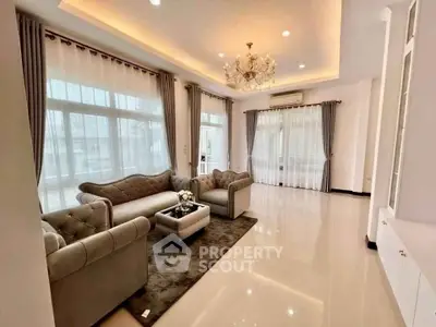 Luxurious living room with elegant chandelier and plush seating in a spacious, well-lit area.