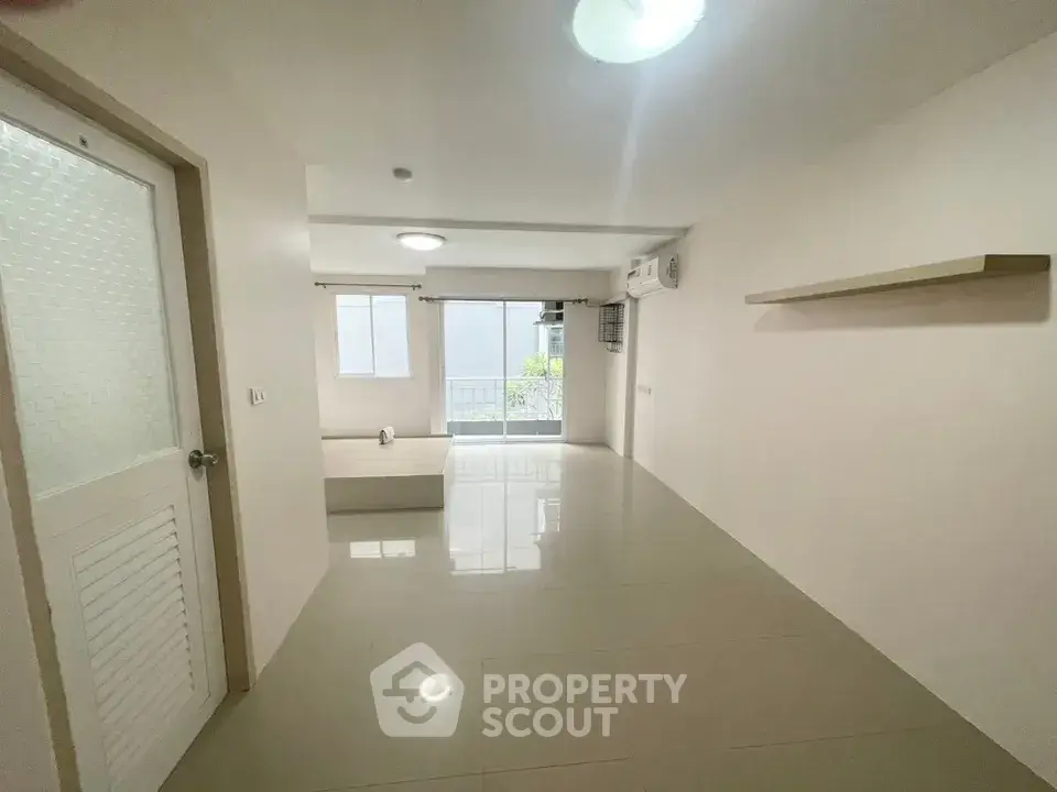 Spacious unfurnished living room with large window and modern lighting.