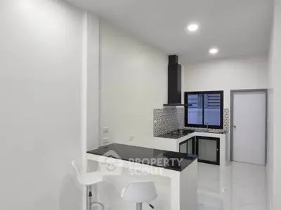 Modern kitchen with sleek black countertops and stylish backsplash in a contemporary apartment.