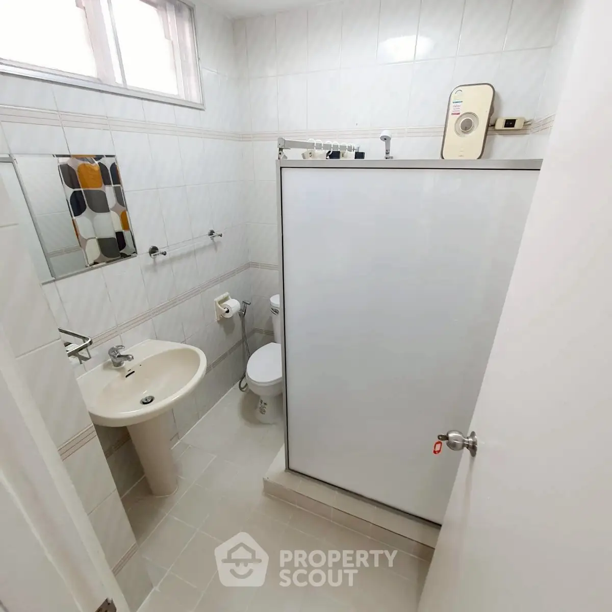 Compact bathroom with modern fixtures and tiled walls, featuring a shower and small window.