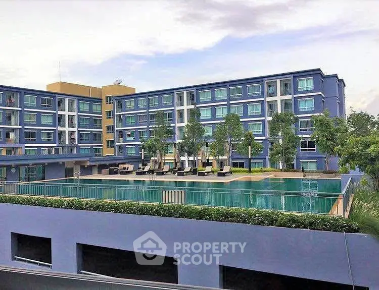 Modern apartment complex with a large swimming pool and lush greenery.