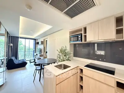 Modern open-layout kitchen with sleek appliances and cozy living area, featuring a large window with a view.