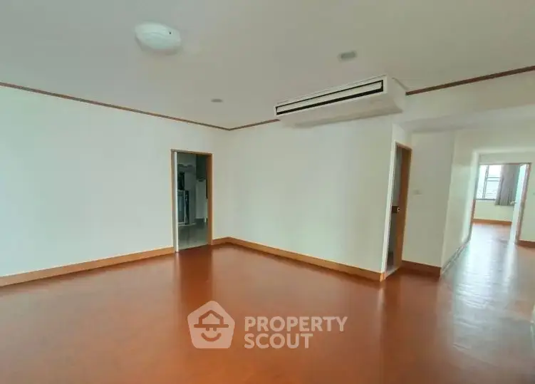 Spacious empty room with wooden flooring and air conditioning, ideal for customization.