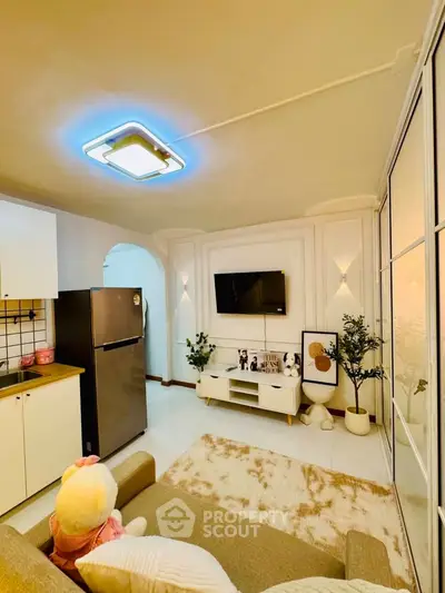 Modern living room with stylish decor and open kitchen layout, featuring cozy seating and wall-mounted TV.