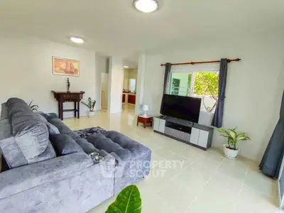 Spacious living room with modern decor and large TV, perfect for relaxation.