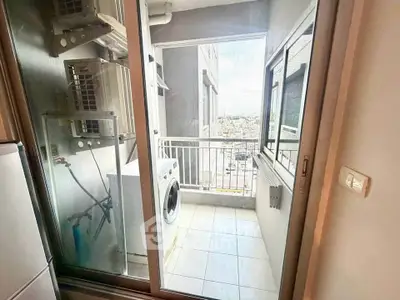 Compact balcony with washing machine and city view, ideal for urban living convenience.