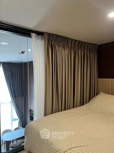 Modern bedroom with floor-to-ceiling windows and elegant curtains, offering a glimpse of a stylish living area.