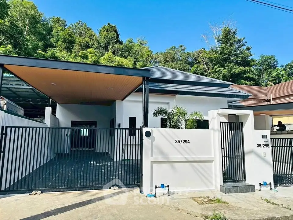 Modern single-story house with sleek black gate and lush greenery backdrop